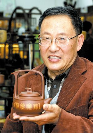 毛国强和他制作的《涤尘提梁壶》，这把壶已升值150%。 重庆晨报记者 杨新宇 摄
