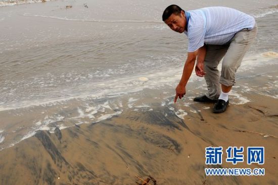 　　7月25日，在河北省乐亭县浪窝口一处海滩，乐亭县水产养殖协会会长杨基珍向记者介绍他们发现油污的情况。最近一段时间以来，不断有网民发帖爆料称河北乐亭疑遭中海油渤海漏油污染，导致海滩被污染、渔业遭重创。究竟当地的海域是否受到中海油蓬莱19－3漏油的污染，水产养殖是否因此而遭受重创，其周围环境和居民目前的生活状况如何，新华社“中国网事”记者带着这些热议话题赶赴乐亭进行实地调查。新华社记者巩志宏摄