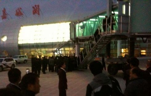 飞机备降后，嘉峪关机场的工作人员引导乘客通过廊桥进入候机楼等待。网友 图