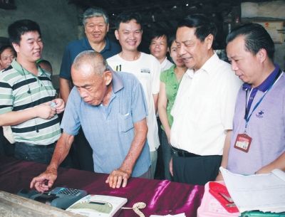 　　为了城乡和谐发展，澄迈县创造实施了“8+2”工程，以此推进城乡基本公共服务均等化，成效显著。图为县委书记杨思涛(右一)陪同中农办主任陈锡文(右二)率领的专题调查组在村头小店内观看一农民老大爷使用pos机转款。操戈摄