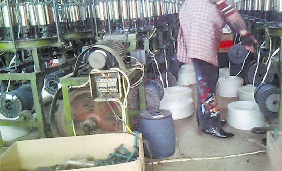 图为工人用黑棉纱纺线