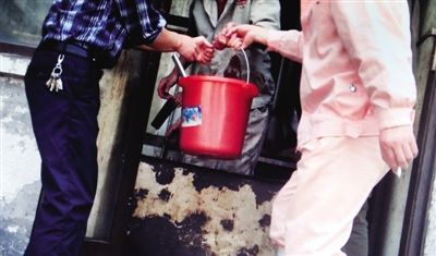 宰杀车间，一工人用桶接猪血，拿到血豆腐加工车间制作。