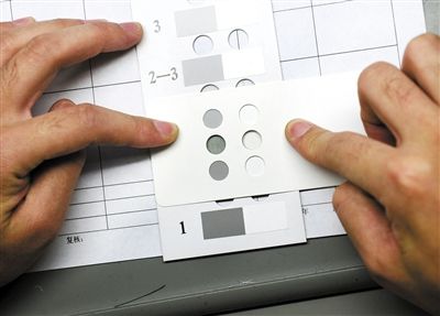 图1：检测人员用“灰色样卡”比对样本颜色级别。