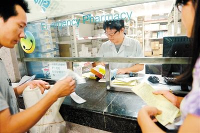 　　7月1日零时20分，在市人民医院取药窗口，就诊的患者查看处方和药费单。 深圳商报记者 薛云麾 摄