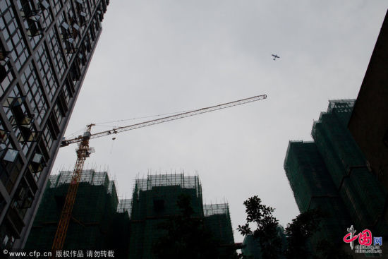 2012年7月7日，四川省绵阳市，一家飞机从在建的万达广场上方飞过。  摄影 刘行喆 图片来源：cfp