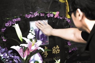 7月14日，万佛园，一位失独家长抚摸着孩子的照片。北京多名失独父母经常相约去墓地。