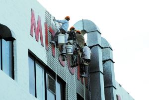 工人正在粉刷被烧黑了的厂房外墙。李刚摄