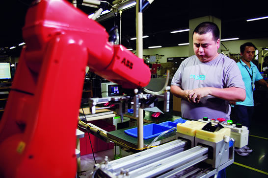 雷柏鼠标工厂引进了70部ABB的机器人，生产总监等邱伟正在进行电子产品自动化生产试验。