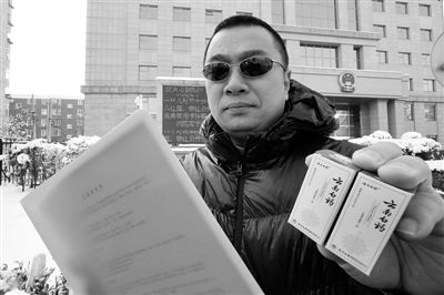 王海在法院门口向记者出示起诉状和证据。记者 曹博远 摄