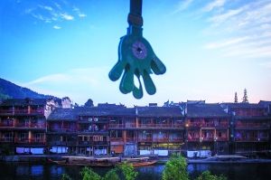 　　凤凰古城，一个拍手器挂在树上。五一小长假， 凤凰游客数量相比往年同期是增加还是减少，政府数据与普通商户的感受差异很大。 早报记者 杨深来 图