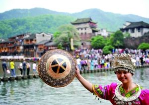 凤凰古城自从收“进门费”后，游客减少，商家不满。图为今年“五一”期间，一名游客身着苗族服饰在凤凰古城拍照。新华社发