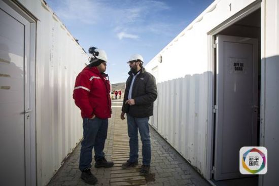 图为先锋营地电站总工程师内斯托·阿亚拉(右)与工人交谈(新华社记者 叶书宏摄)