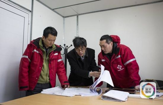 　　图为中国工程师倪四平(左一)饶孝国(左二)和崔志成(右一)在研究施工图纸(新华社记者 叶书宏摄)