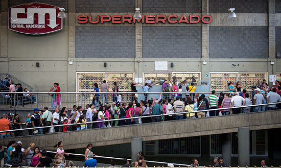 资料图：委内瑞拉首都加拉加斯，一家超市外人们排起长龙。他们通常排队数小时，期望能买上洗涤剂、卫生纸或食用油等日用品