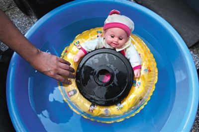 塑料娃娃套上游泳圈，放上5公斤的重物后，最终沉入水中。6月18日，记者测试五款儿童游泳圈的浮力，一款不合格。新京报记者 薛珺 摄