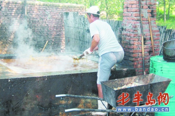 　　一名工人正在炼油，脏油上面浮着一层渣子。