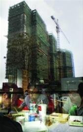 　　排队的购房者正在吃午餐，窗外是尚未完工的心仪楼盘。