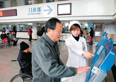 一名患者(前)在上海市徐汇区斜土社区卫生服务中心，用医保卡在自助分诊机挂号。