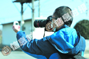 　　信息时报摄影记者何剑辉，在福岛20公里警戒线处测量核辐射量。