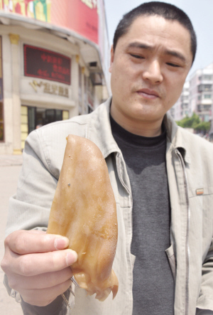 　　一位市民展示买到的人造猪耳朵 新华社发