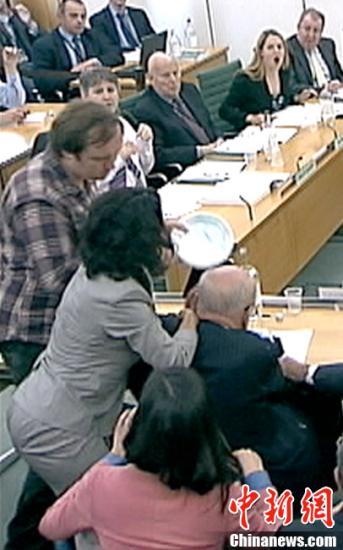 　　北京时间7月20日凌晨，在英国议会就《世界新闻报》窃听丑闻质询默多克父子时，一名男子突然从听众席窜起，手拿餐盘，跨过默多克旁边的人对其袭击，身后其妻子邓文迪迅速起身反击，第一时间抬手准备给袭击者一巴掌。袭击者随后被警方带走。