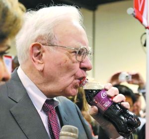  巴菲特自曝养生秘诀就是一天喝5瓶可乐，图为去年5月巴菲特在开股东大会前喝可乐。