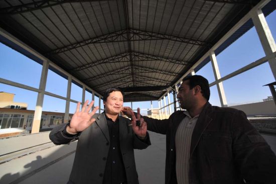 　　余明辉与他的阿富汗合伙人正在沟通钢厂投产计划，谈话中合伙人轻柔地为他捏去粘在其领口的线头。晨报记者 陈征 摄影