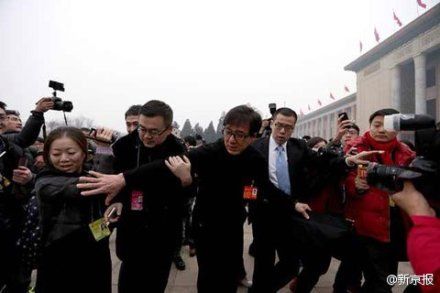 被围堵的明星委员。成龙在人群中回身试图拉住即将摔倒的媒体记者；姚明试图溜边走却没能成功……