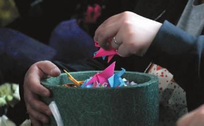 4月29日，家属将纸鹤放进装有亲人骨灰的降解罐中 