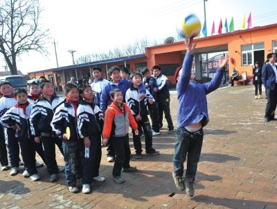 2012年3月20日，孩子们兴高采烈地玩着志愿者送来的新排球。 当天，50多名志愿者来到通州区的农民工子女学校“通州明星学校”，为这里的孩子送来大量的体育器材，并和孩子们一起为校园操场进行了平整。（资料图片）京华时报记者胡雪柏摄