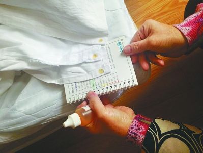  检查人员将试剂滴在酒店公用纺织品上，20秒后将其显示的颜色和测试卡上的颜色进行对比，即可判断公用纺织品的酸碱度是否超标。上述颜色显示的结果是偏碱性。 本报通讯员 王芙蓉 本报记者 邹伟摄