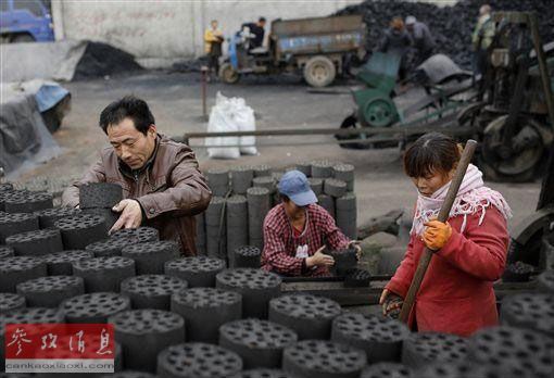 资料图片：一家煤炭加工厂的工人在搬运蜂窝煤。（美联社）