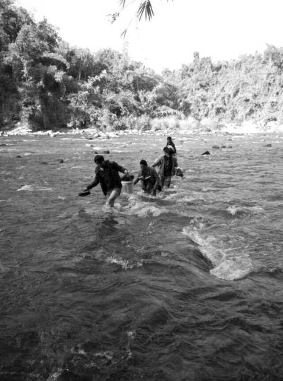 送木材的中国司机赤脚蹚河躲避追捕。受访者供图