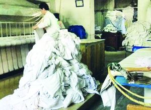 一团团白大褂、床单、病号服、手术衣等随意堆放。 图片转自辽沈晚报聊沈客户端