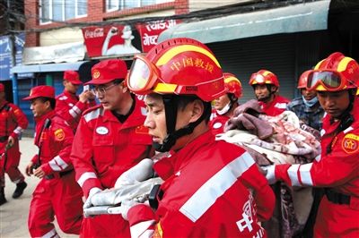 26日，尼泊尔首都加德满都，中国国际救援队搜救队员从坍塌的楼房中抬出一名幸存者。新华社记者 白阳 摄