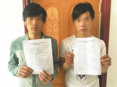 听说要为自己恢复名誉，在外打工的李晓岭(左)和齐少欢(右)专程赶回家，两人展示了国家赔偿决定书。新京报记者 王大鹏 摄