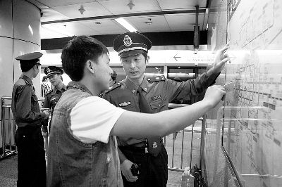 轨道交通执法队员在地铁内帮乘客找线路 摄/顾欣