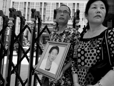 林家人手捧林立峰的遗像，站在法院外神情黯然