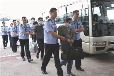 昨日，公安人员在北京首都机场押解6名境外在逃经济犯罪嫌疑人。新华社记者 李明放 摄