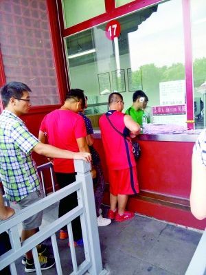 排第三个的红衣男子插队帮男游客买票。