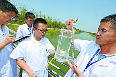 昨天，在南水北调团城湖明渠水闸口，南水北调水质监测中心的工作人员采集水样，仔细记录各项数值，保障本市用水安全。 记者 饶强 摄