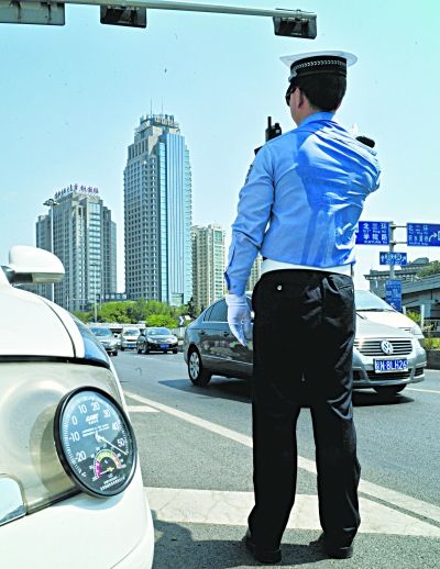 昨日，骄阳似火，汗水已浸透了交警的后背。 张耀 摄