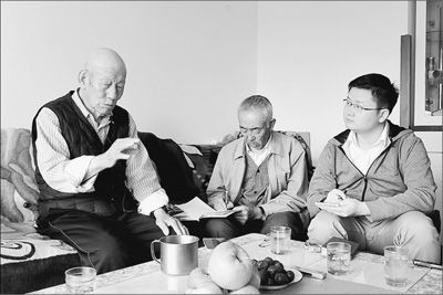 今年九十一岁的王荣华老人(左)在家中接受采访，讲述他亲历的抗战故事。记者杨明方摄