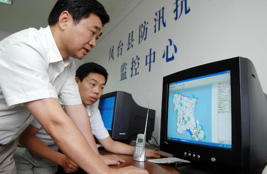 凤台县淮河防汛指挥部指挥长姚多咏(左)借助防汛监控系统进行决策调度