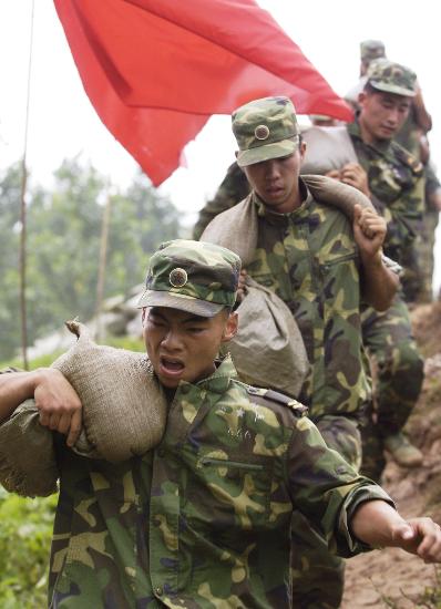 官兵在搬运沙袋封堵渗漏点7月21日,南京军区73092部队的官兵在搬运