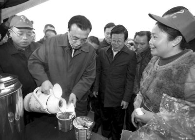      14日，李克强在高速公路服务区为农民工倒水泡面。
