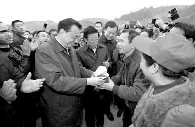      李克强将热腾腾的方便面送到农民工手中。