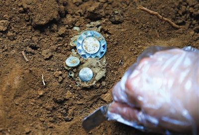  工作人员在现场挖掘出的远征军遗骸，以及徽章、袖扣。 A18-19版摄影/新京报记者 吴江