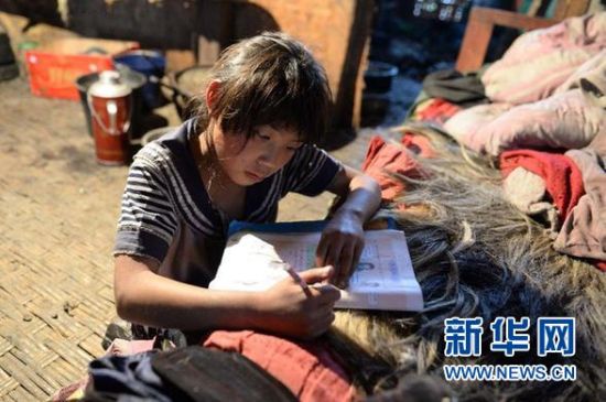 在云南省怒江州福贡县木克基村，一名孩子趴在床上做作业，她的家里没有桌子（3月28日摄）。 新华社记者 胡超 摄