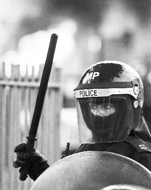 　　8月8日，伦敦东部的一名防暴警察在一辆被暴徒烧毁的汽车旁“严防死守”。